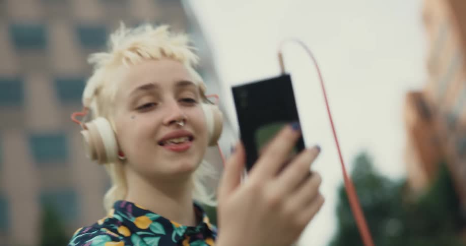 Blonde woman talks on video call and moves smartphone around to show her surroundings