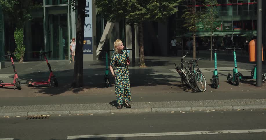 Young woman wearing a colorful outfit tries to cross a busy city street