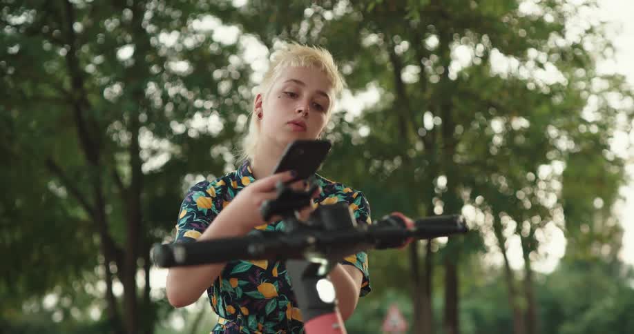 Blonde womanuses smartphone to access electric scooter