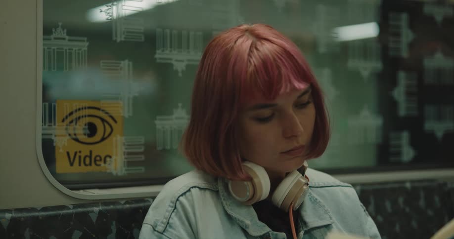 A young woman reads a book while sitting in a subway train