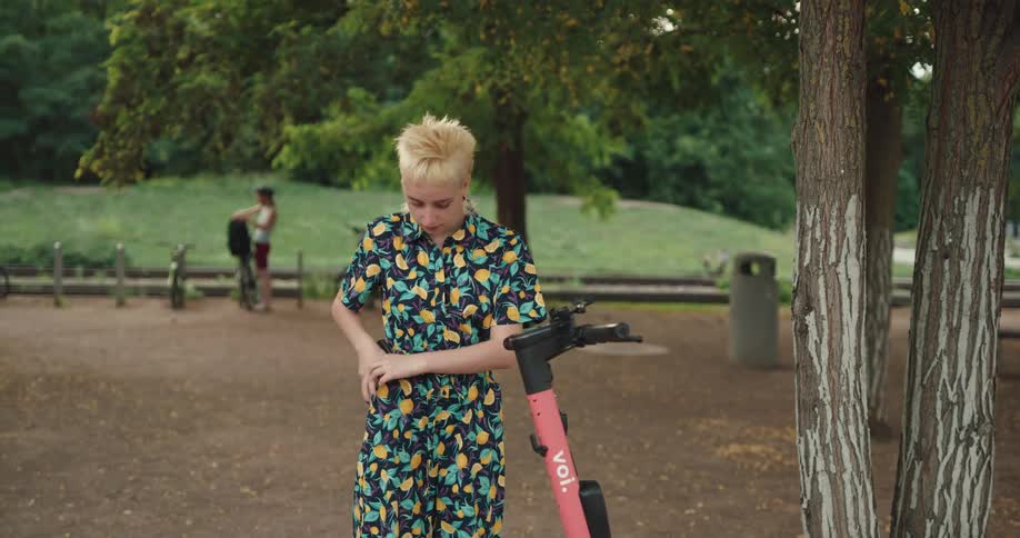 Woman access shared scooter in park with a smartphone