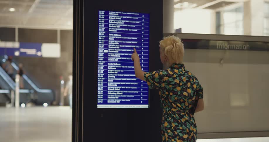 Young blonde woman checking arrival screen at the airport