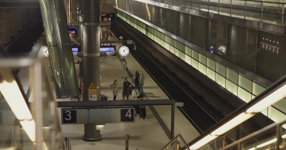 People await the subway on a platform in a station