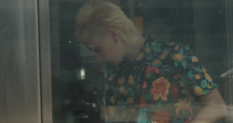 A woman walks into an elevator and pushes a button to go up