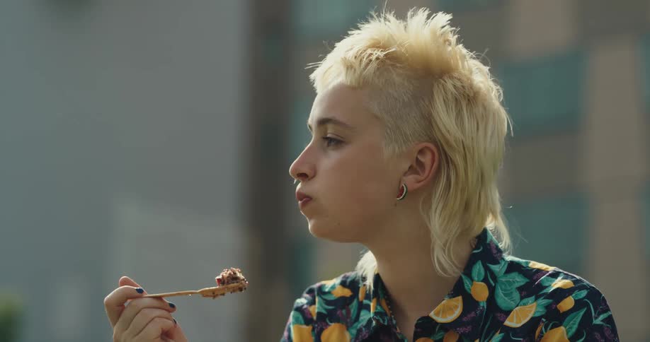 A girl is eating food from a bowl outside