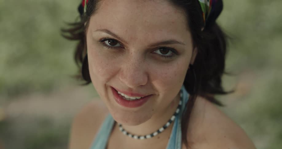 A woman is smiling and sitting on the grass outdoors