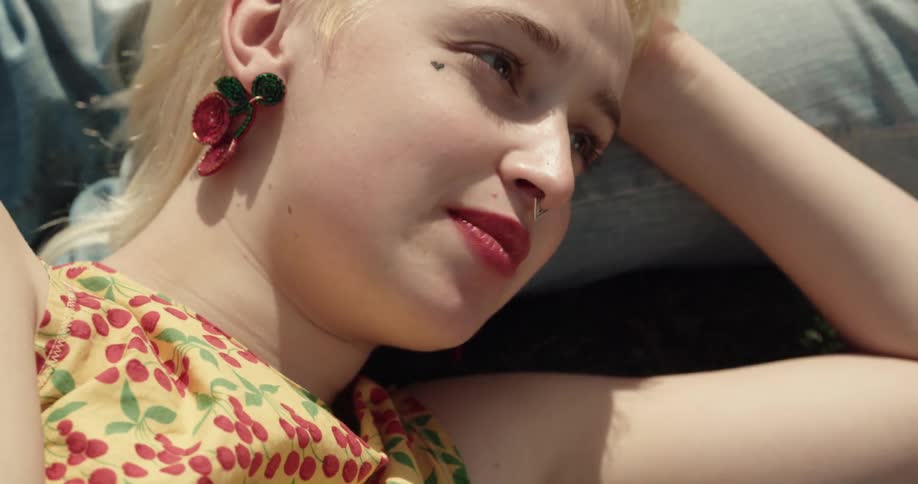 A girl is lying on another girls lap and talking as she passes her beer and snacks