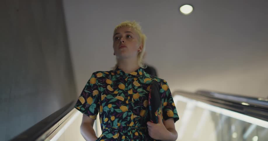 A woman looks at her cell phone on the escalator