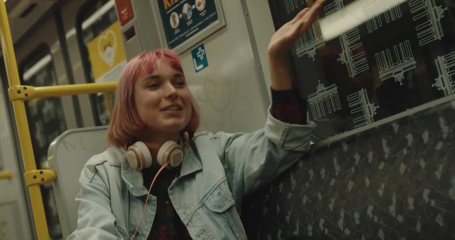 A young woman laughs while talking to someone on a subway