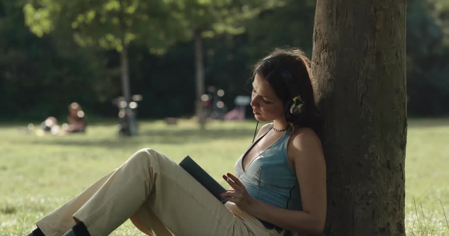 A woman is reading a book at a park during spring