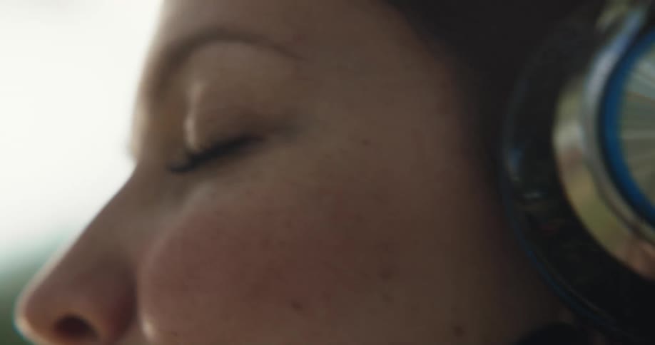 Close up of woman with silver blue headphones listening to music