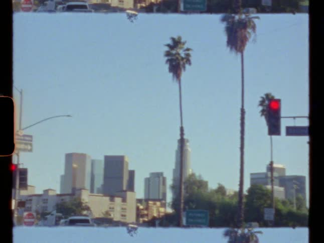 Palm trees on the street in front of the city skyline at morning caught on vintage film