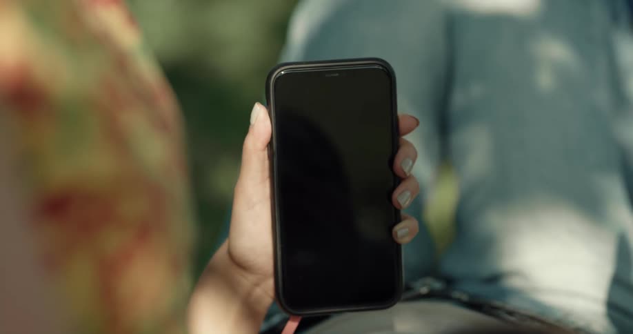 A girl is sitting outside using her cell phone