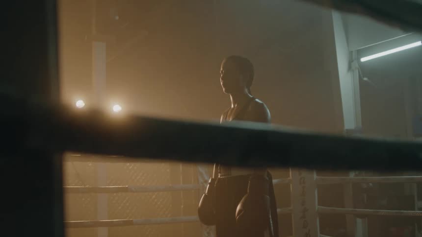 A female boxer stands in a boxing ring
