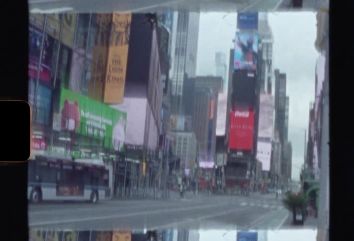 Digital displays attached to the facade of buildings lining a street in a metropolis during the day