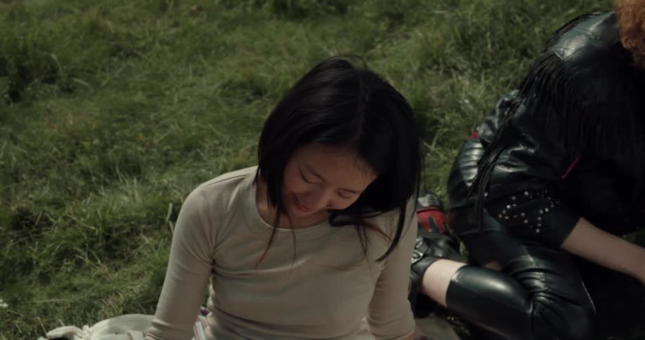 A woman lays her head on another womans legs as they relax outdoors together