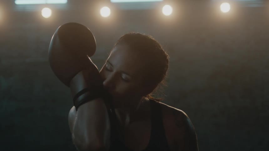 A woman unties a boxing glove with her teeth then takes it off her hand