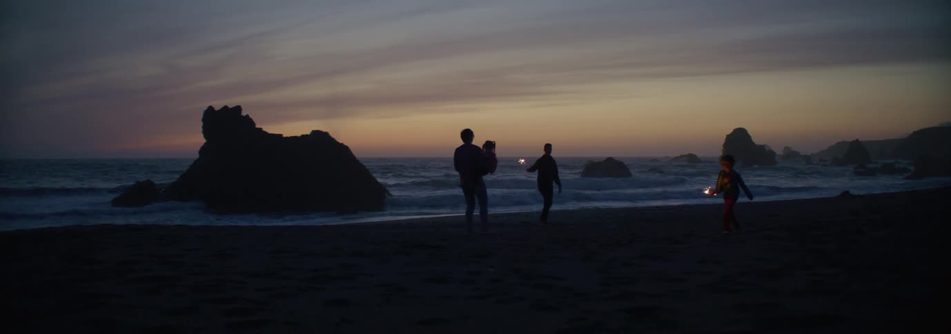 A family having fun with sparklers at the beach at sunset