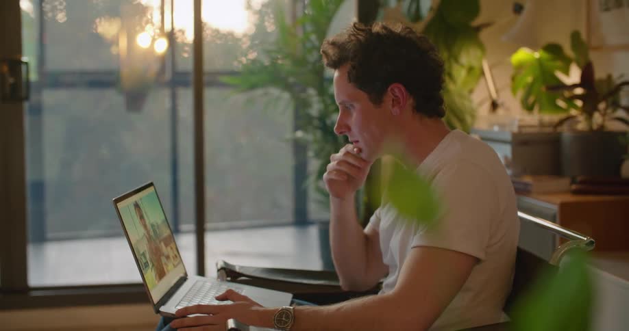 A man is sitting in a chair with a laptop computer having a video conversation with another man