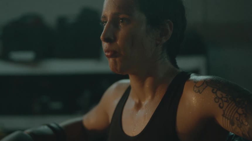 A female boxer standing in the corner of a boxing ring