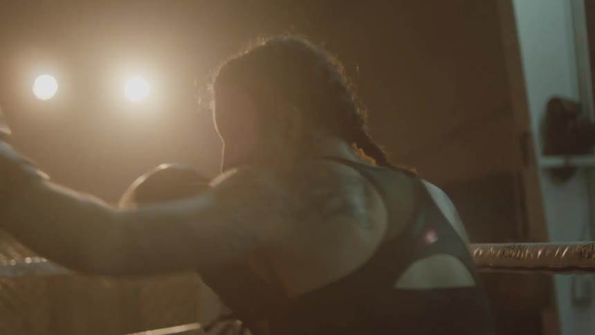 Female boxer with braids tattoo and sports bra trains in boxing ring