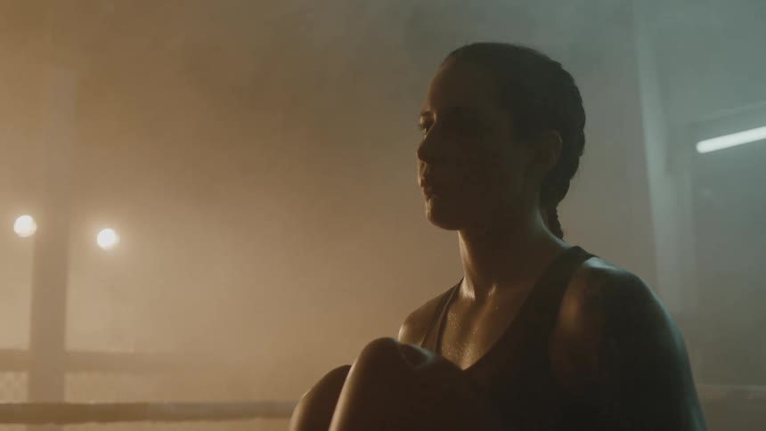 Female boxer with braids sports bra fight trunks and boxing gloves stands in the ring