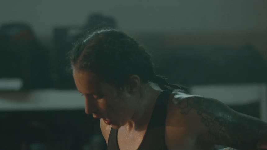 A woman shakes sweat off her face before going back to the center of a boxing ring