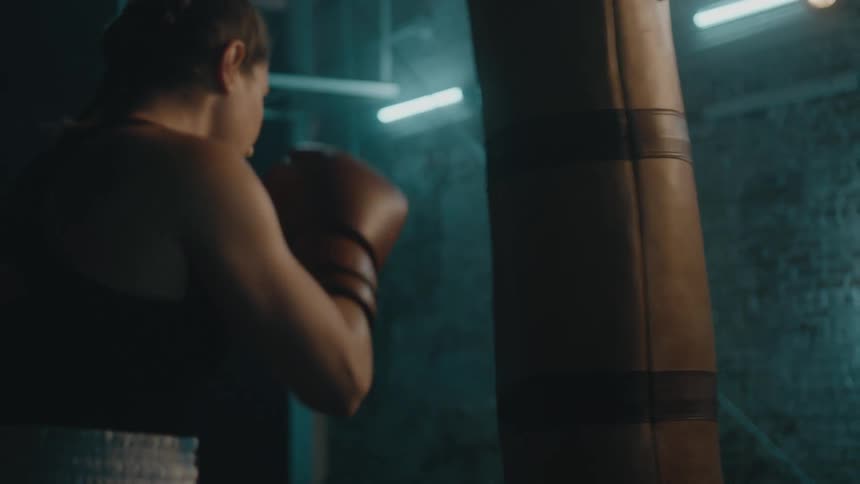A female boxer trains by striking a punching bag