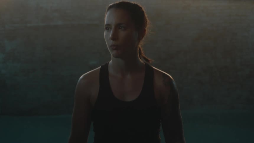 Female boxer with braids sports bra boxing gloves and boxing trunks stands in the ring