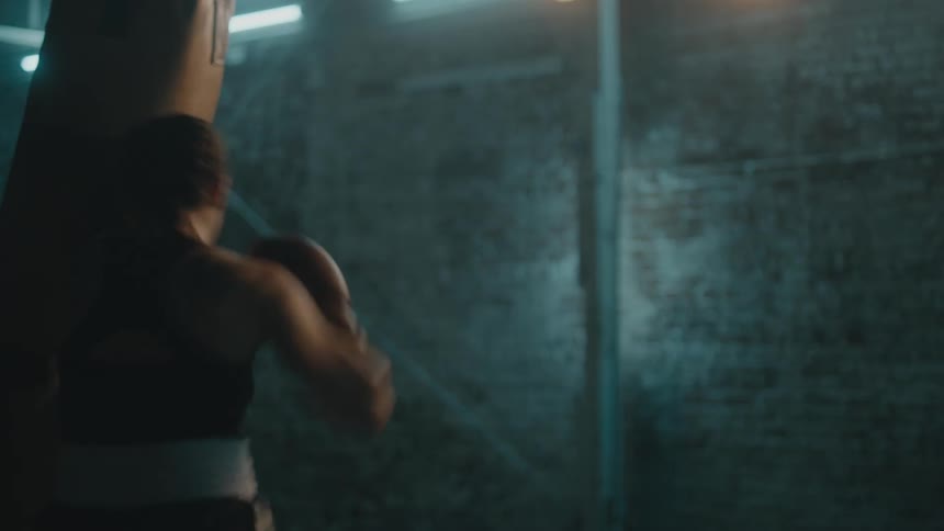 A woman is in a room and boxing by herself