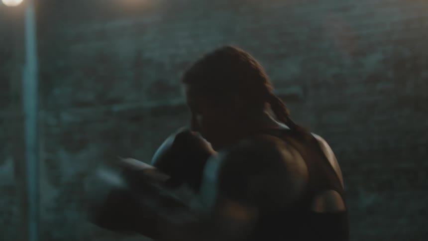 A woman is boxing by herself in a brick building