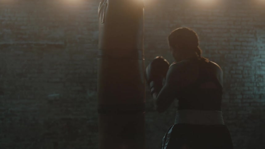 A woman is boxing a punching bag indoors