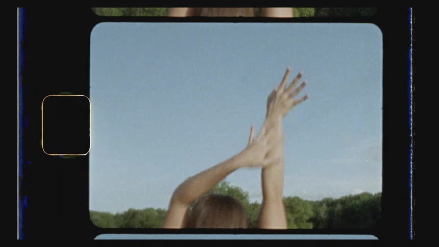 A woman dances outside with her arms in the air