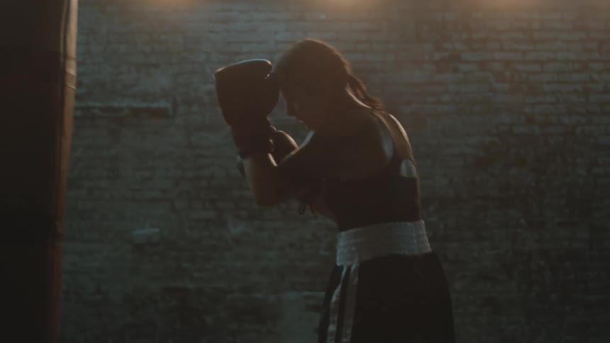 A woman is boxing by herself in an empty building