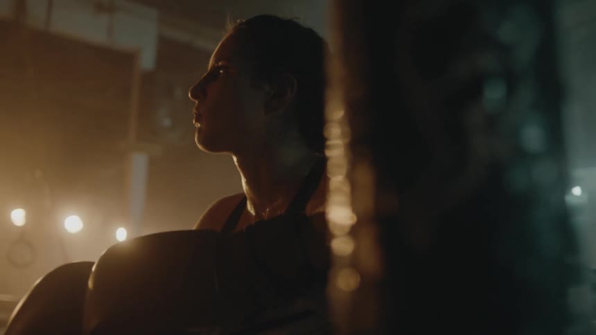 Young strong muscular woman wearing boxing gloves ready to fight in a dimly lit ring