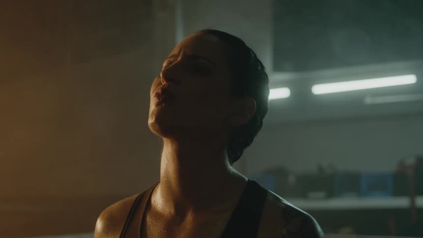 Female boxer with braids and sports bra stands in the boxing ring
