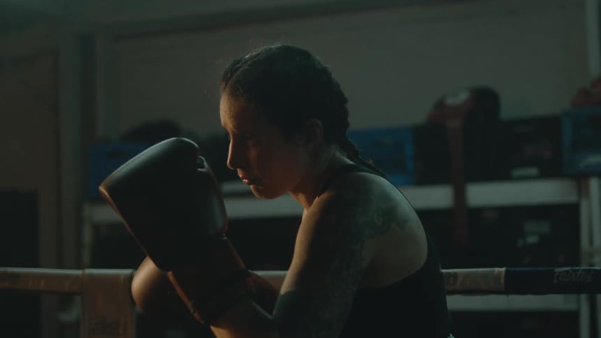 Female boxer with braids sports bra and boxing gloves trains in the boxing ring