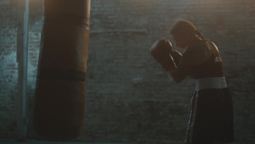 A woman hits a punching bag in the gym