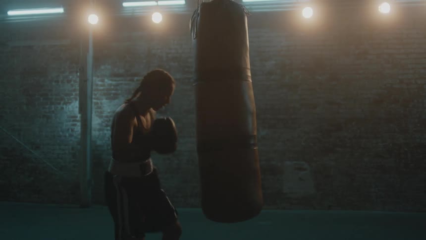 A woman is punching the heavy bag with gloves