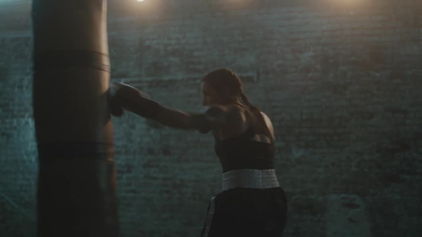 A woman is boxing by herself in a room