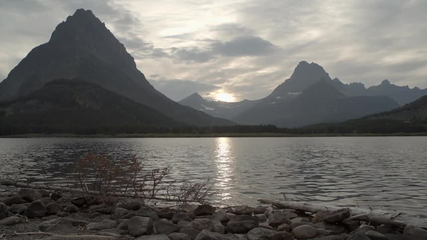 A lake leads to a mountain range on a cloudy day