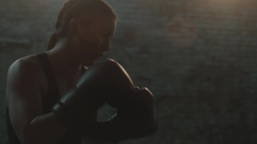 A woman is boxing by herself indoors
