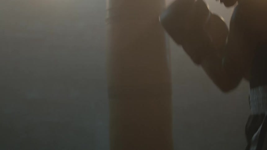 A female boxer shadow boxes in a dimly lit room