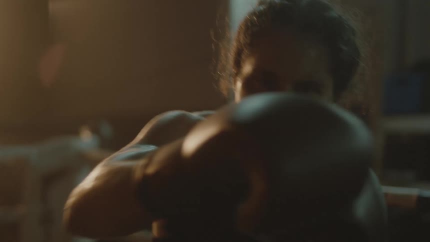 Female boxer with sports bra boxing gloves throws punches in the boxing ring