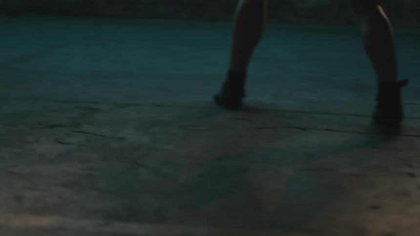 Female boxer moving her feet while boxing over a ring inside a dimly lit building