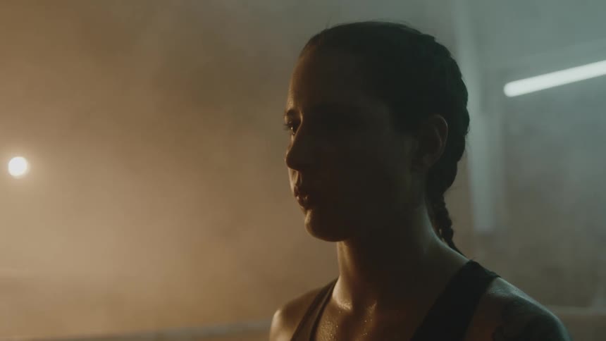 Woman with braids sports bra and tattoo turns around and stands in the ring