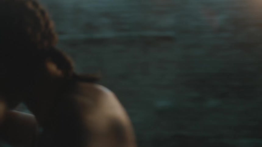 A female boxer strikes a punching bag in a dimly lit room