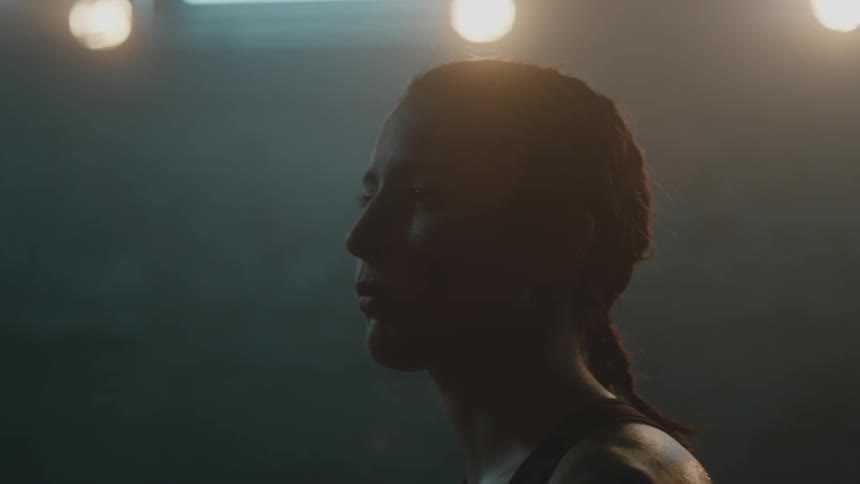 Female boxer with braids and sports bra stands in boxing ring