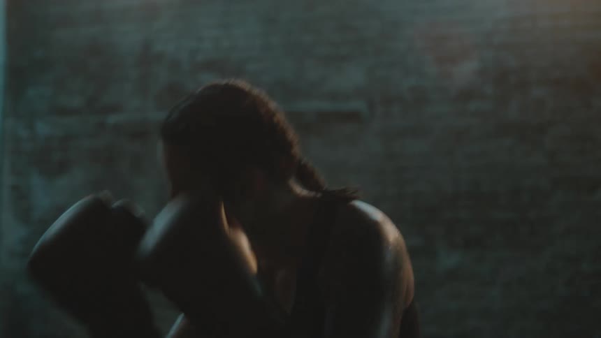 A woman is boxing by herself indoors