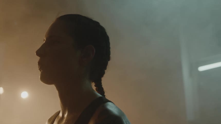 A woman stands in a smoke filled gym